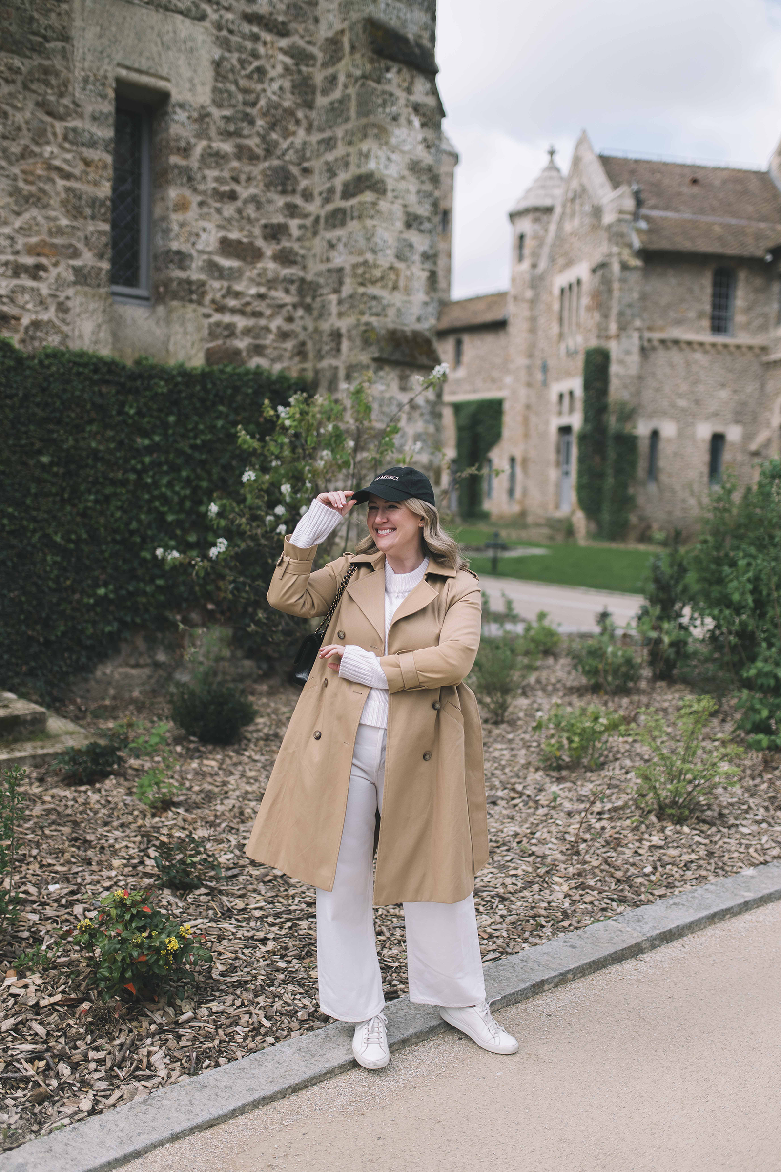  Wit Whimsy Blogger Meghan Donovan shares What to Wear in Paris in the Spring - in photo: Meghan wearing a trench coat and white sneakers in Paris