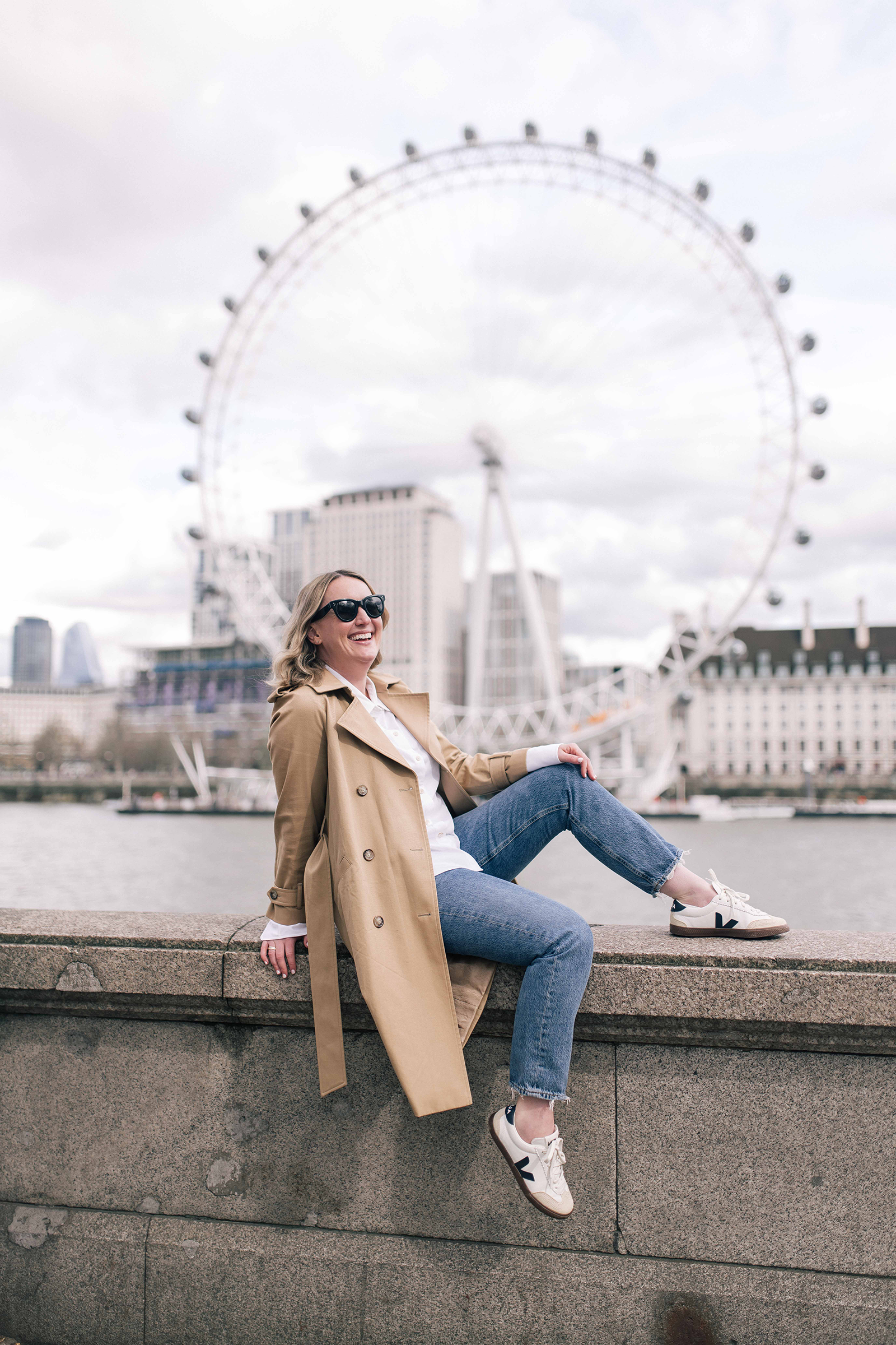 Meghan Donovan posing in front of the London Eye during her trip to London wearing Veja sneakers.